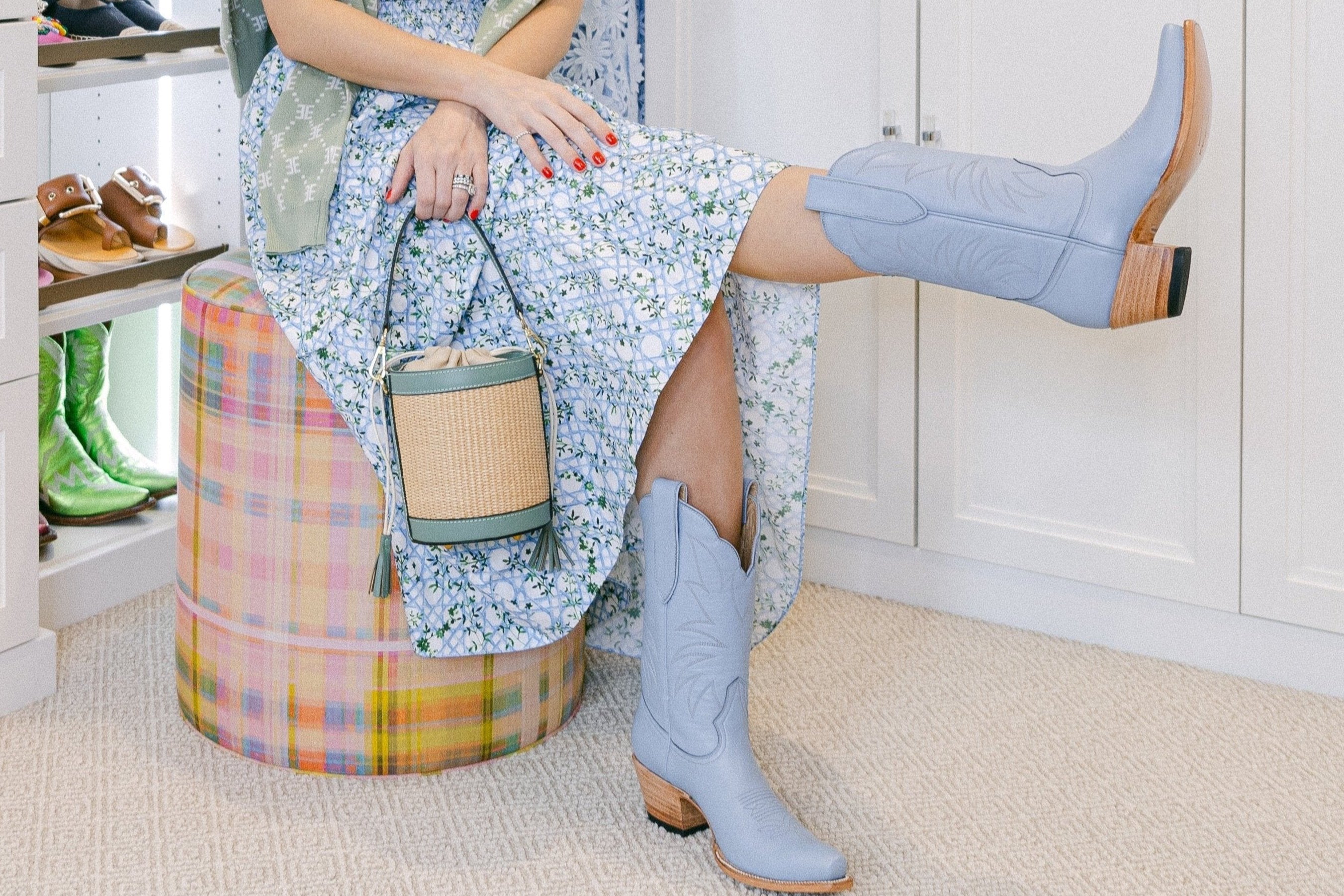 Woman sitting on a colorful stool wearing light blue boots in a room with white walls and wooden floor.
