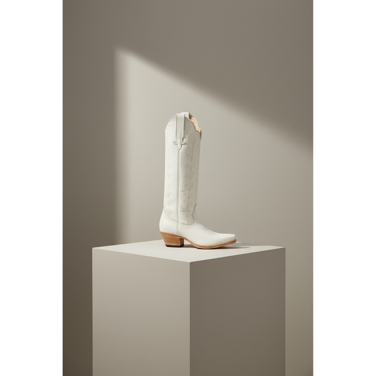 Ivory A-Toe Vine boot displayed on a square pedestal.