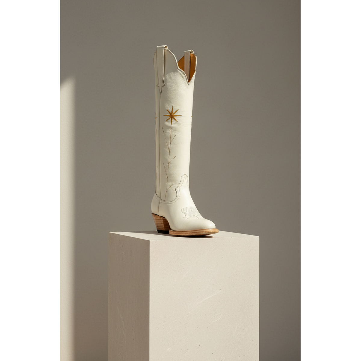 Gold Flower boot displayed in a three-quarter view on a pedestal.