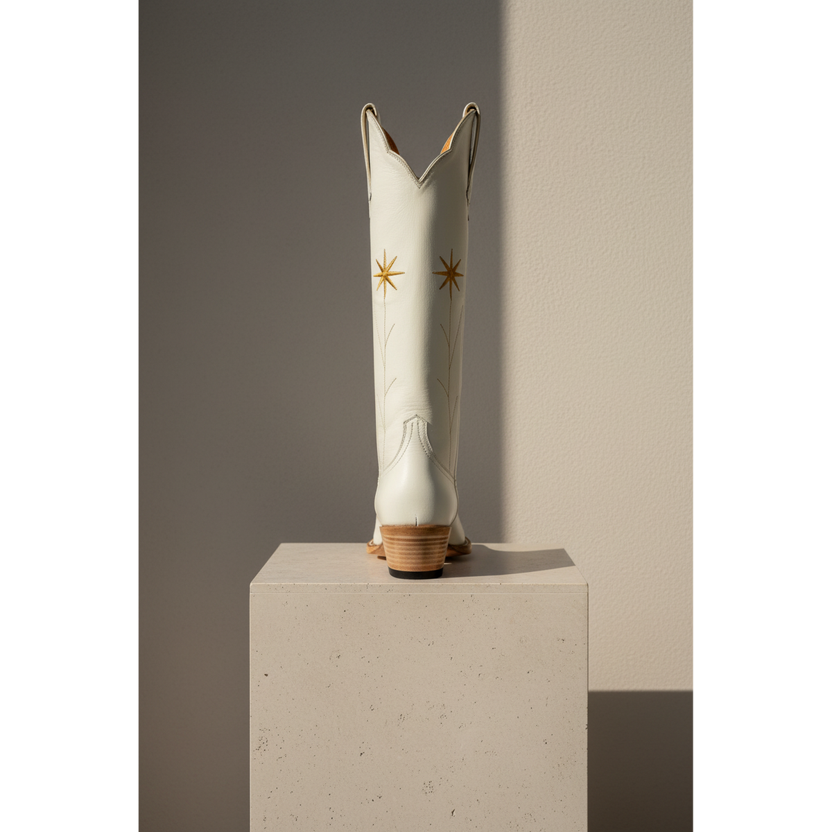 Gold Flower boot displayed from the back on a pedestal.