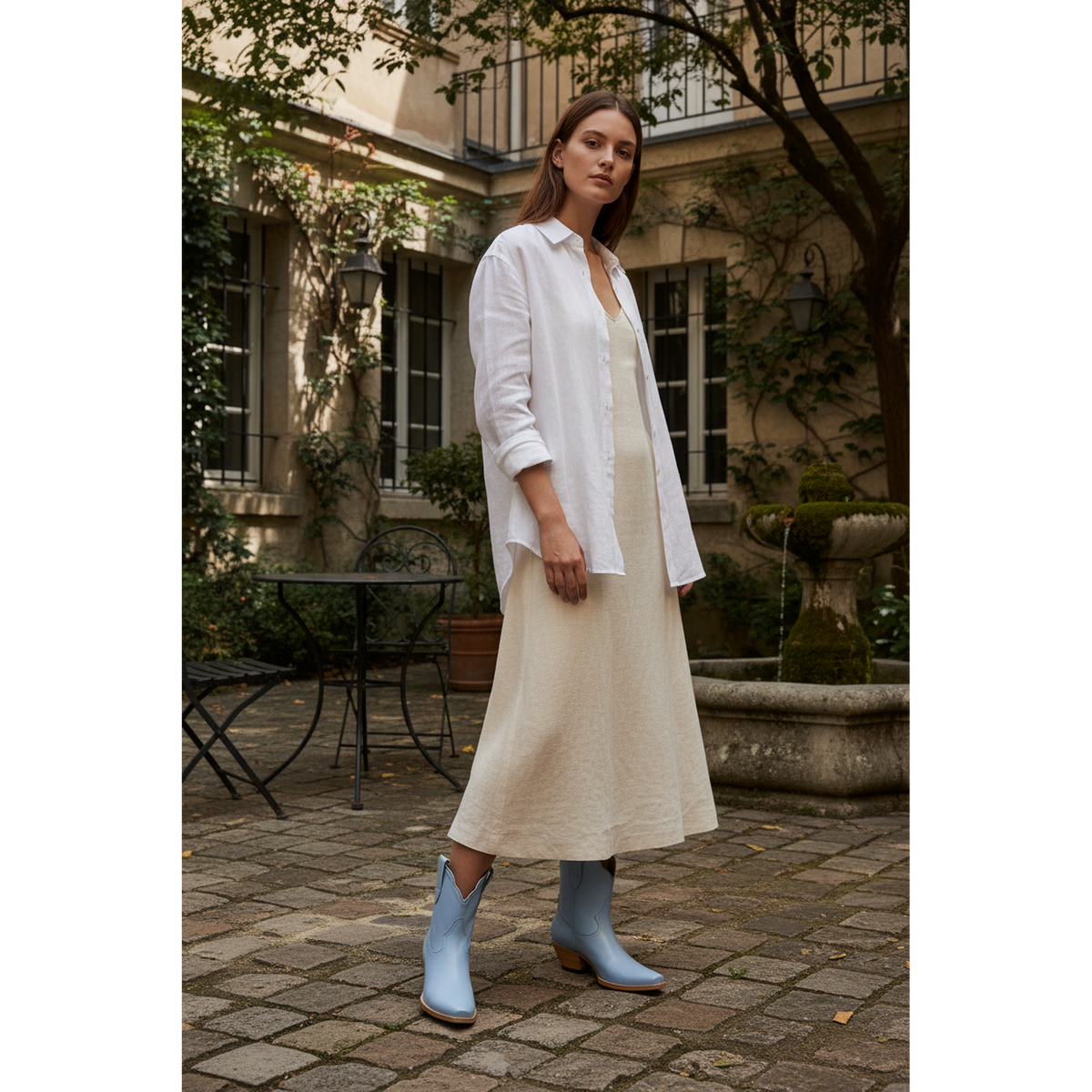 Woman wearing powder blue boots in a courtyard