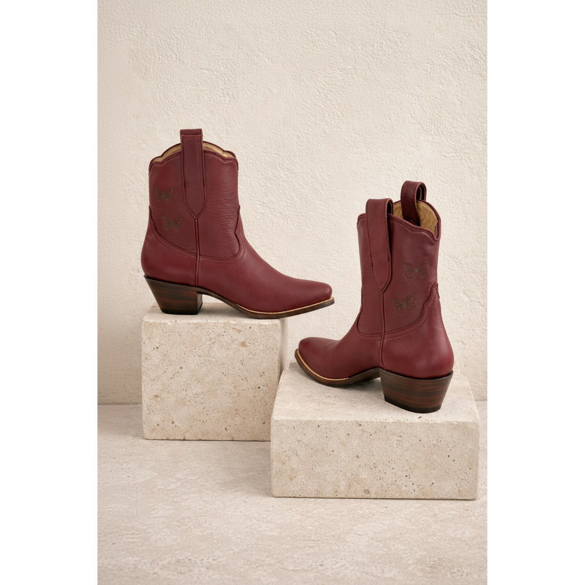 Maroon Mariposa boots arranged on two blocks.