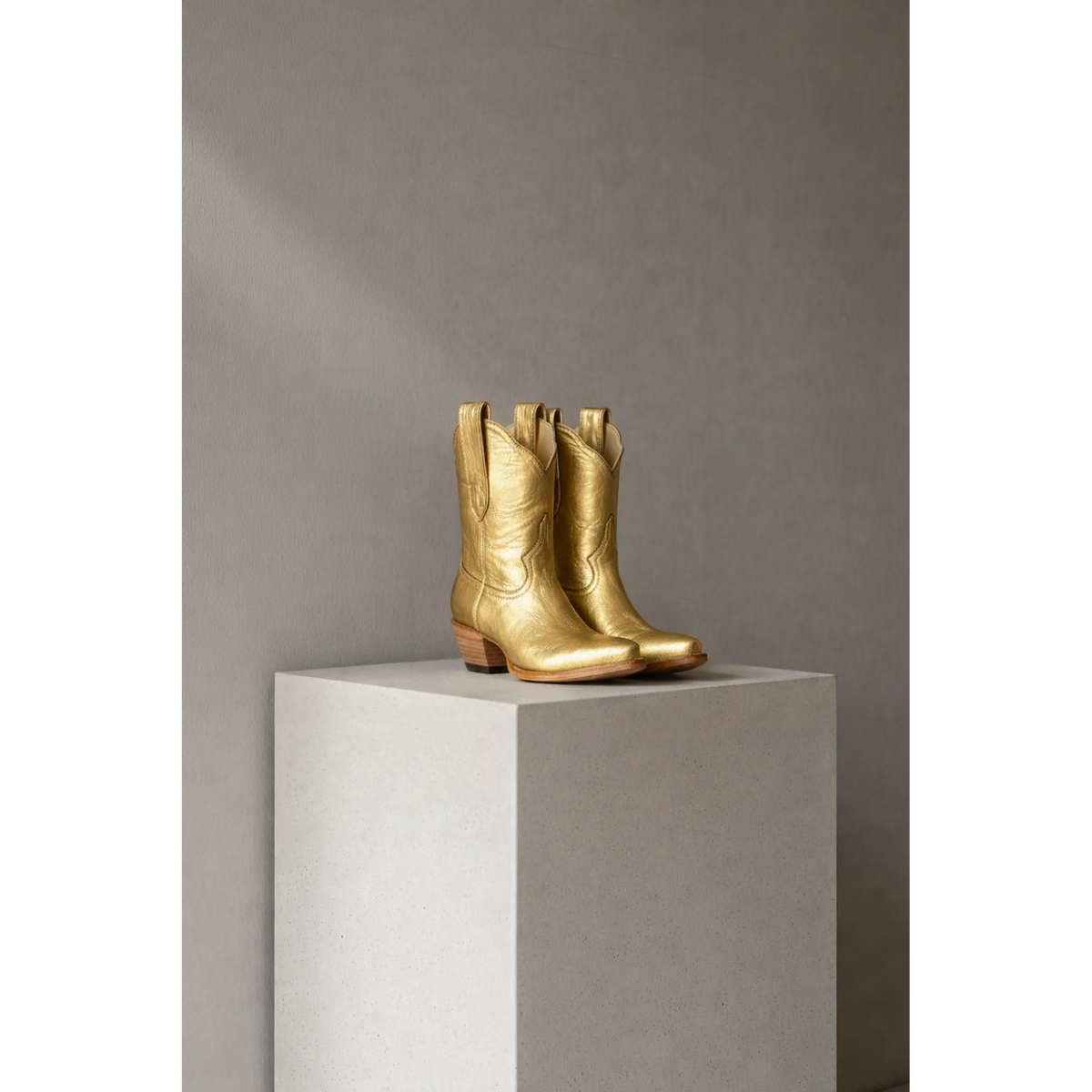 Gold Metallic Payton boots on a stone pedestal