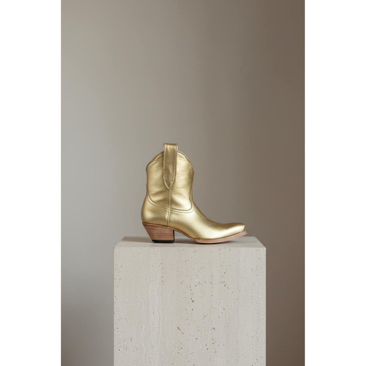 Gold Metallic Payton boot, side view on a stone pedestal
