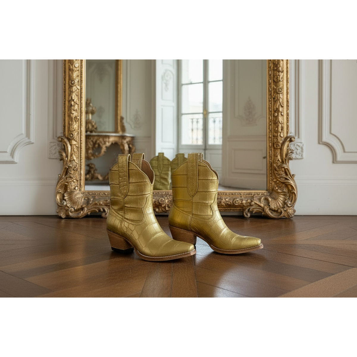 Gold alligator exotic luxury cowgirl short cowboy boots on a wooden floor with an ornate gold mirror in the background.