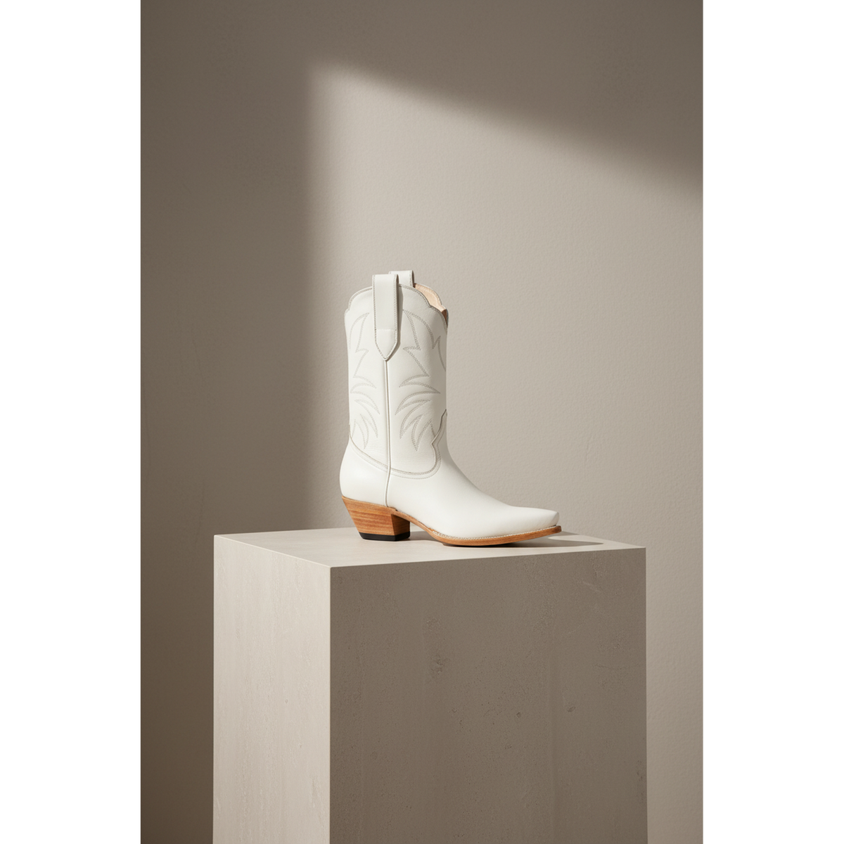 Bone Marjorie Midi boot with tonal outline stitching, shown in profile on a pale pedestal.