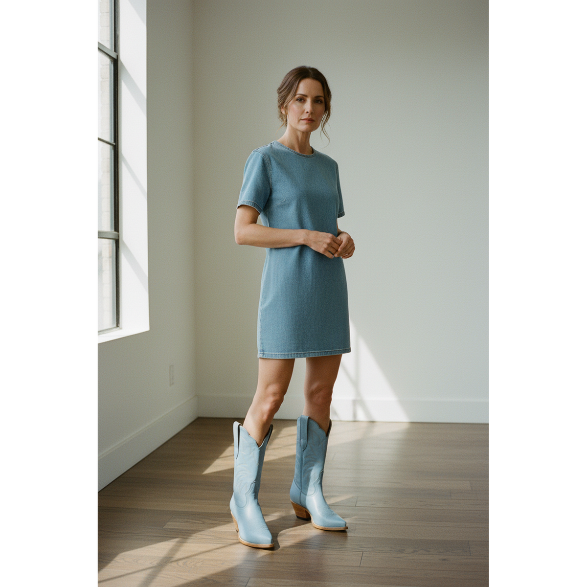 Woman wearing pale-blue midi boots with a short blue dress in a studio.
