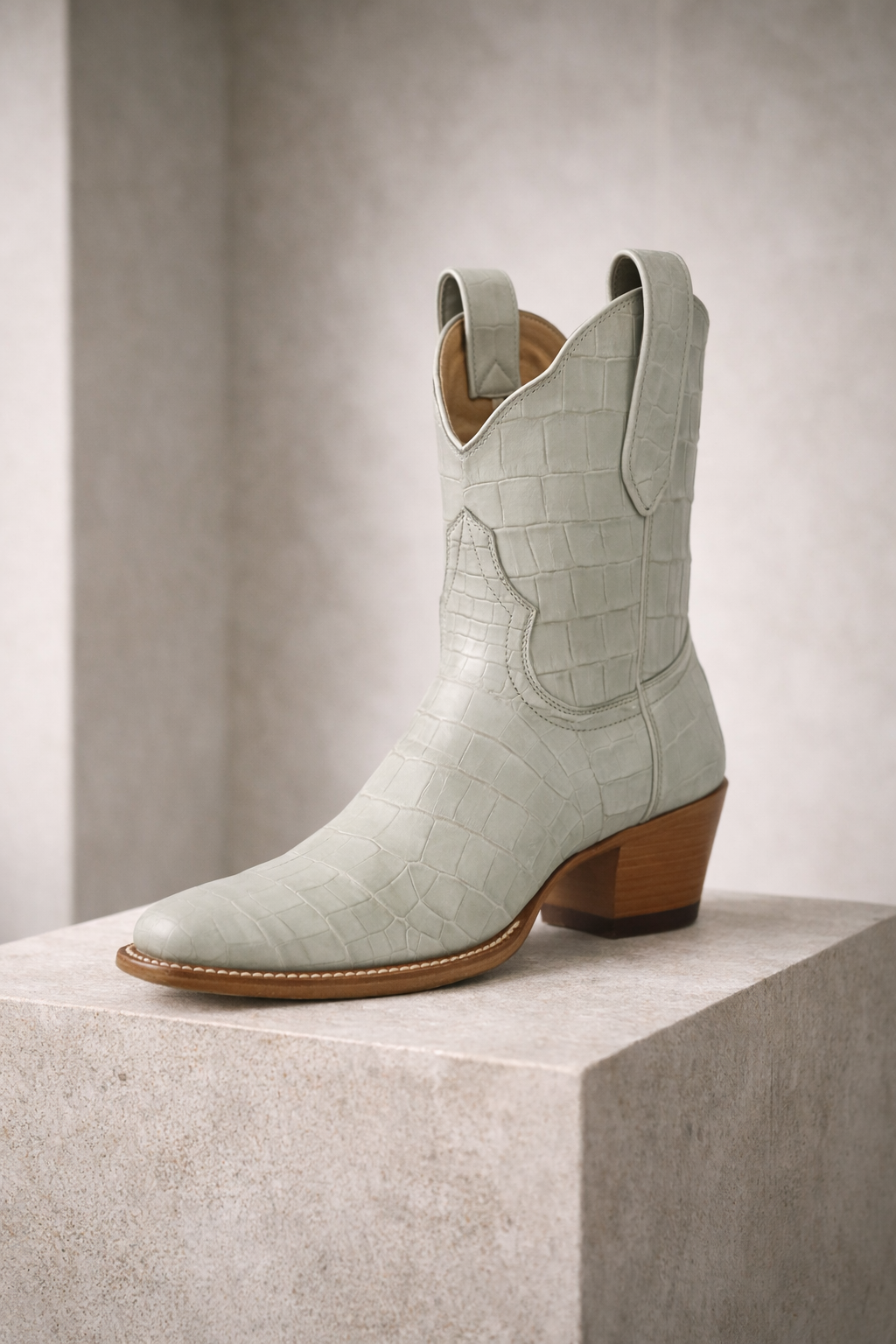 Light blue cowboy boot with brown sole on a light gray background