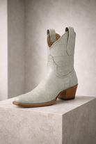 Light blue cowboy boot with brown sole on a light gray background