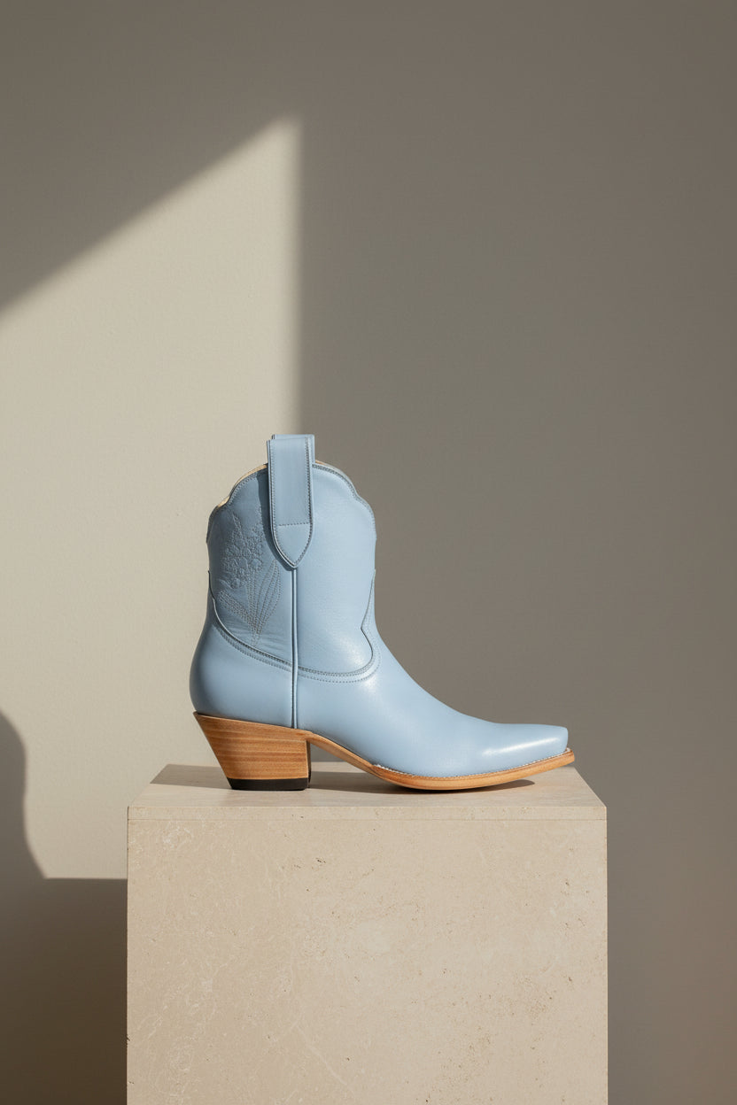 Light blue cowboy boot with brown heel on a white background