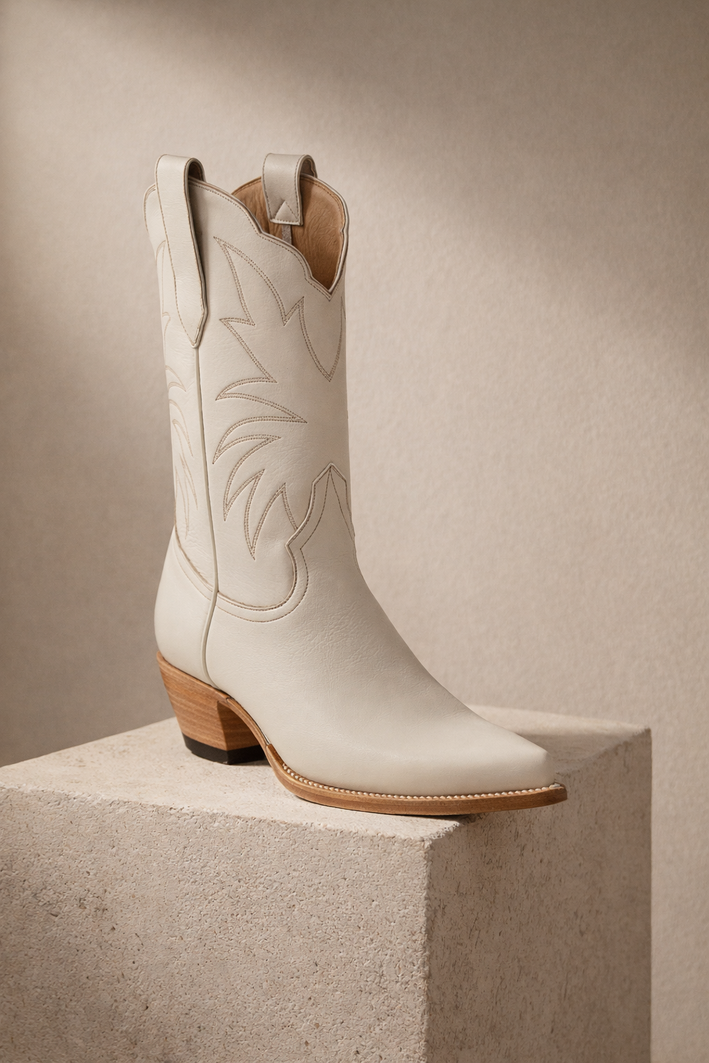ivory cream off White cowgirl cowboy boot with brown sole on a beige block against a beige background bridal 