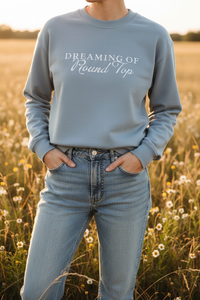 Person wearing a blue sweatshirt with 'Dreaming of Round Top' text in a field.