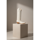 Ivory A-Toe Vine boot displayed on a tall pedestal.