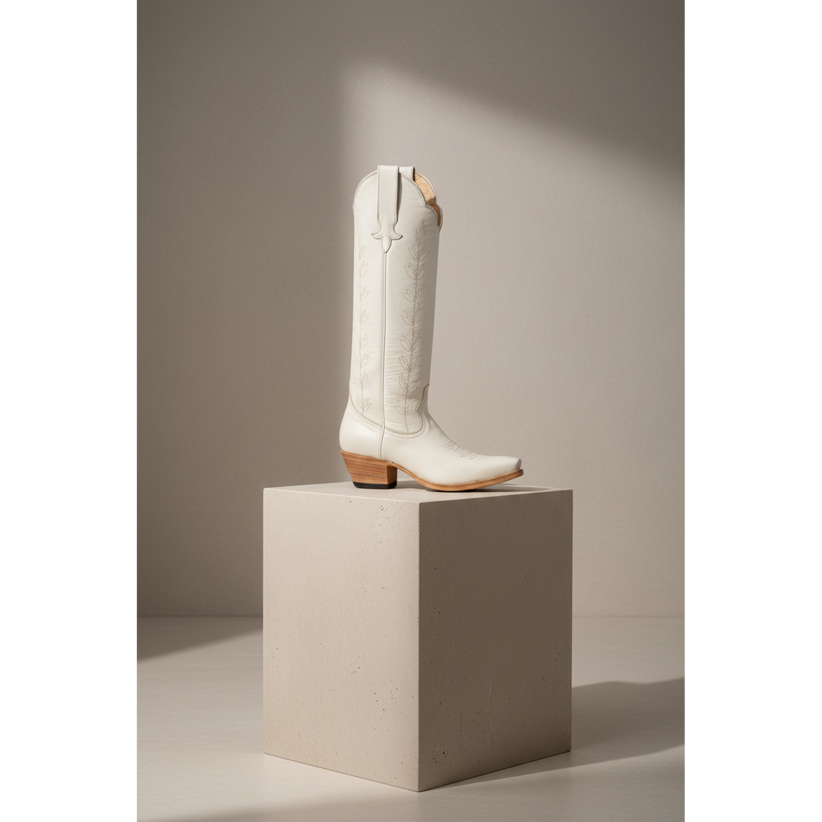 Ivory A-Toe Vine boot displayed on a tall pedestal.