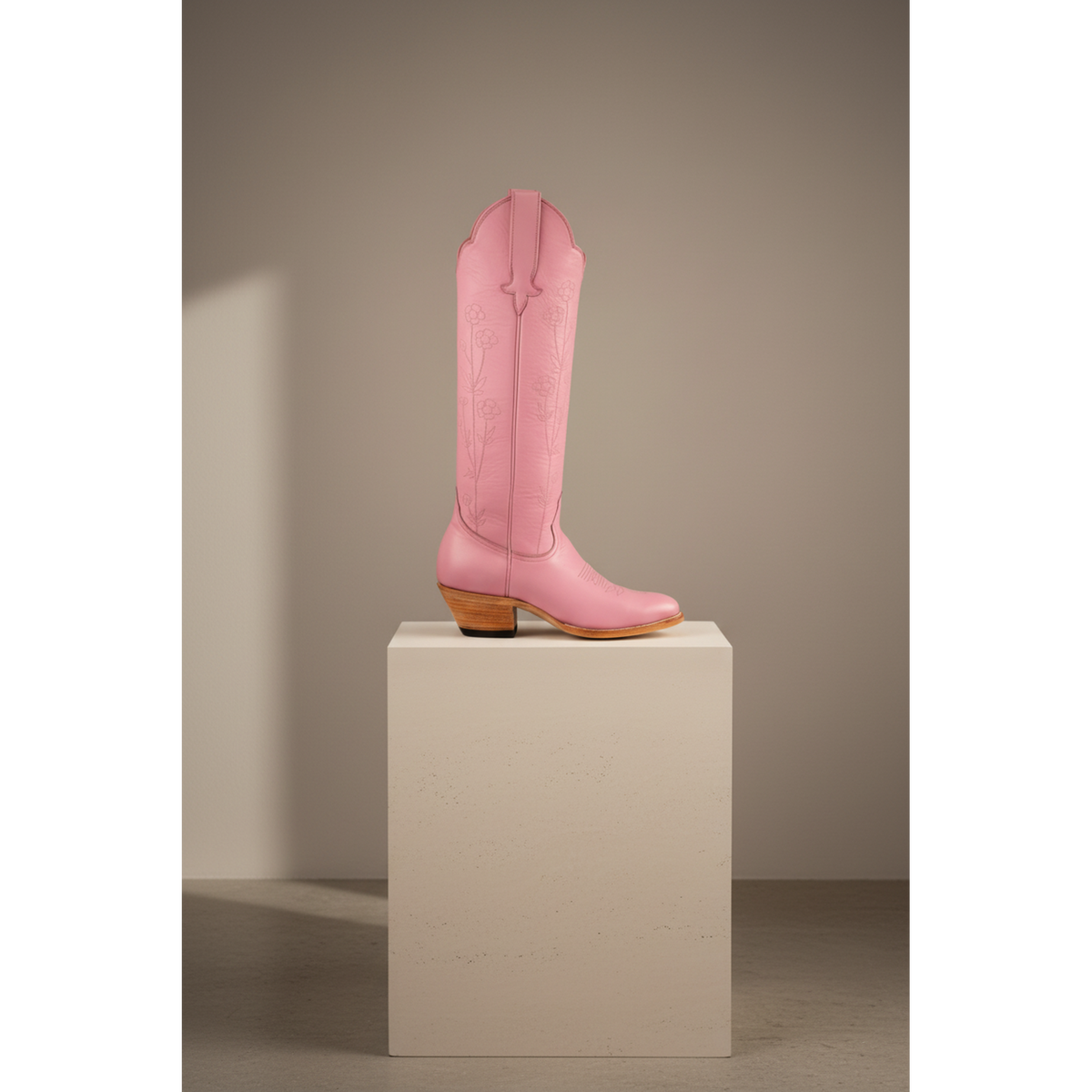 Pink Buttercup boot on a pedestal in a softly lit room