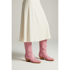 Pink Buttercup boots worn with an ivory skirt
