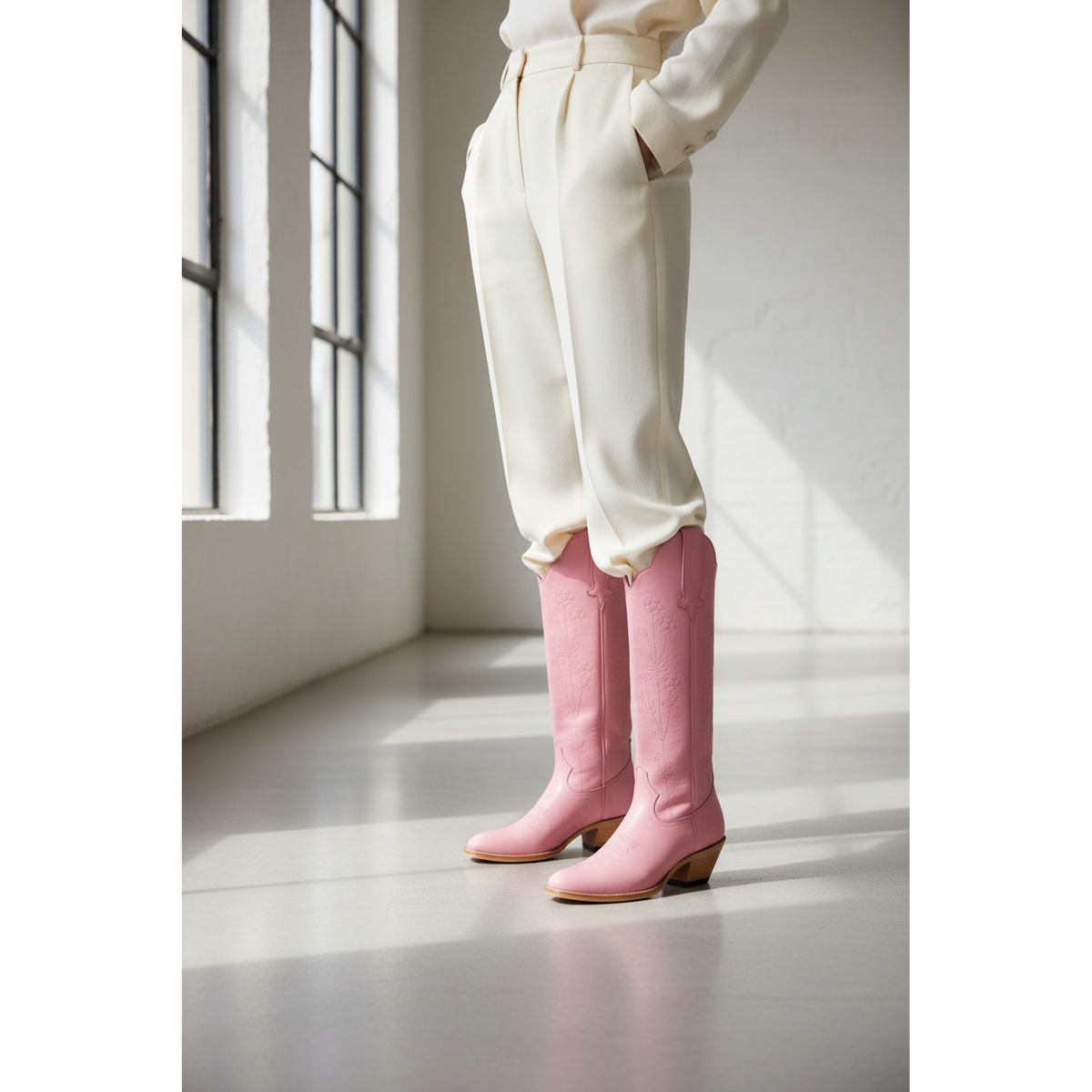 Pink Buttercup boots worn with a cream outfit beside a window