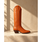 Chestnut tall boot on a stone surface.