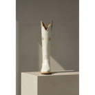Gold Flower boot displayed from the front on a pedestal.