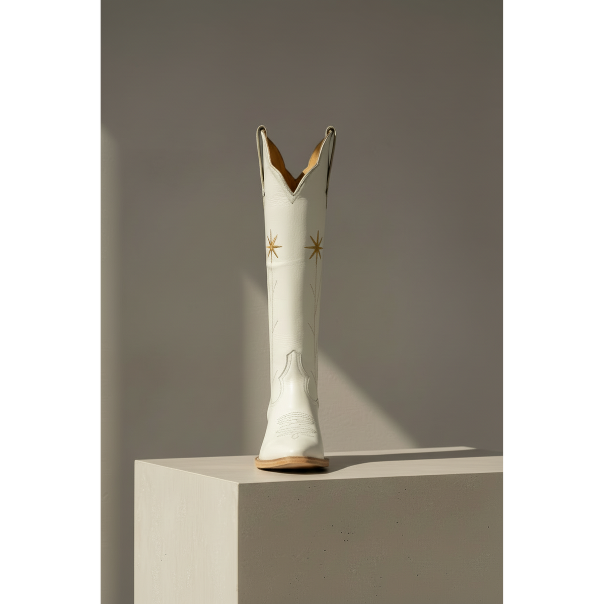 Gold Flower boot displayed from the front on a pedestal.