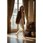 Woman wearing ivory boots with a brown jacket and light trousers.