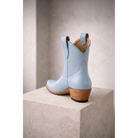Powder blue boot in rear three-quarter view on a stone pedestal