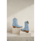 Pair of powder blue boots displayed on stone blocks