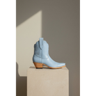 Powder blue boot in side view on a stone pedestal