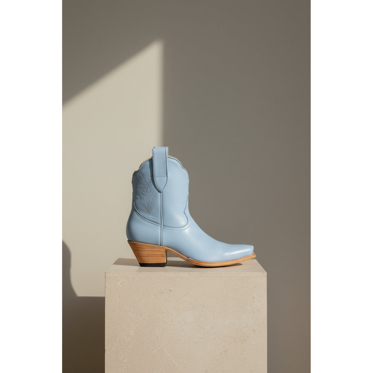 Powder blue boot in side view on a stone pedestal