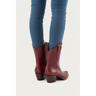 Rear view of maroon Mariposa boots worn with blue trousers.