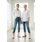 Two women wearing pale-pink boots with white shirts and blue jeans.