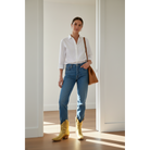 Woman wearing a white shirt, blue jeans, and yellow boots in a room with wooden flooring.