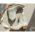 Pair of light gray chalk ivory cream ankle boots with wooden soles on a neutral background tule ribbon bridal alligator exotic short luxury boot cowgirl cowboy white