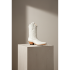Bone Marjorie Midi boot with tonal outline stitching, shown in profile on a pale pedestal.