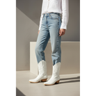 White embroidered midi boots styled with cropped light-blue jeans.