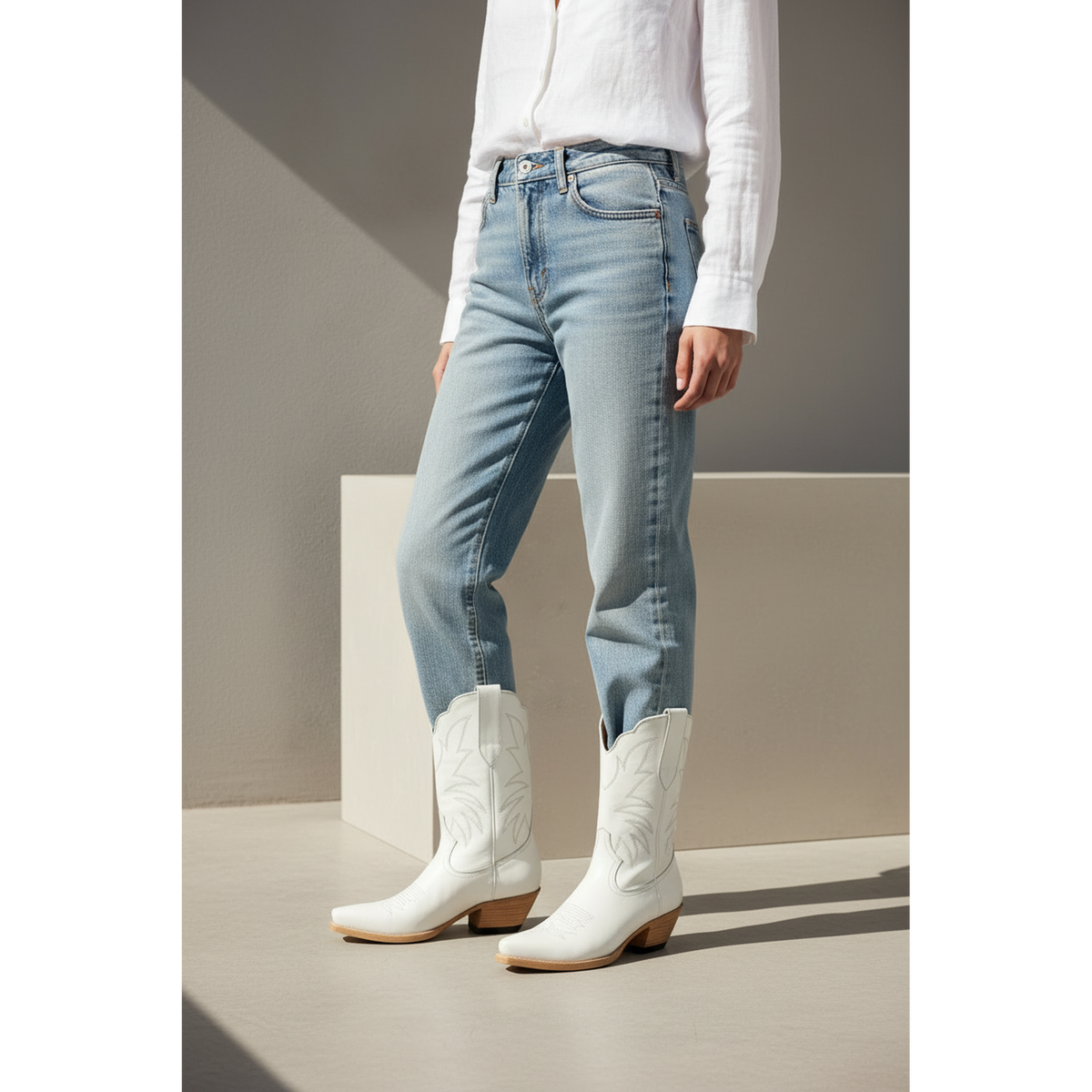 White embroidered midi boots styled with cropped light-blue jeans.