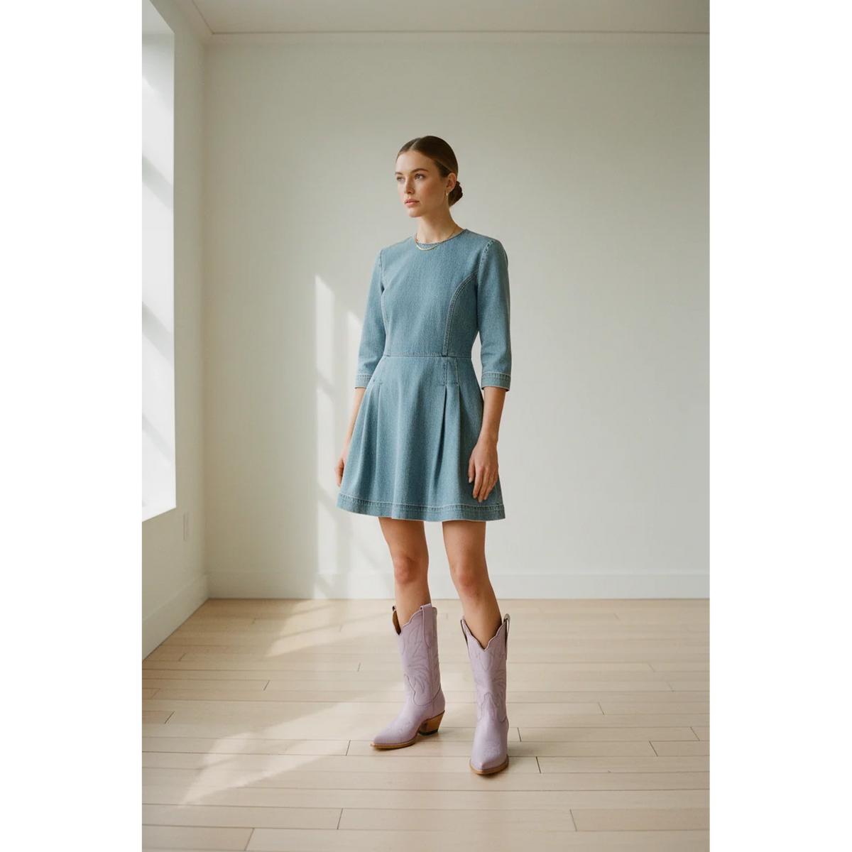 Woman wearing pale-lavender midi boots with a blue dress in a sunlit room.