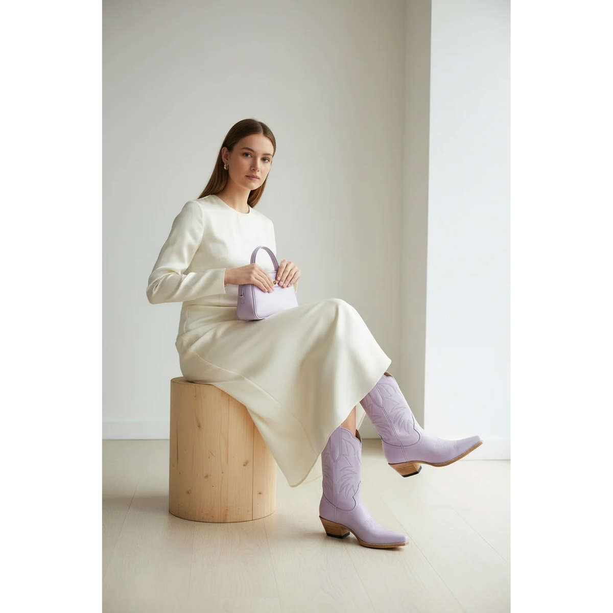 Woman seated on a wooden block wearing lavender boots and a cream dress.