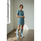 Woman wearing pale-blue midi boots with a short blue dress in a studio.