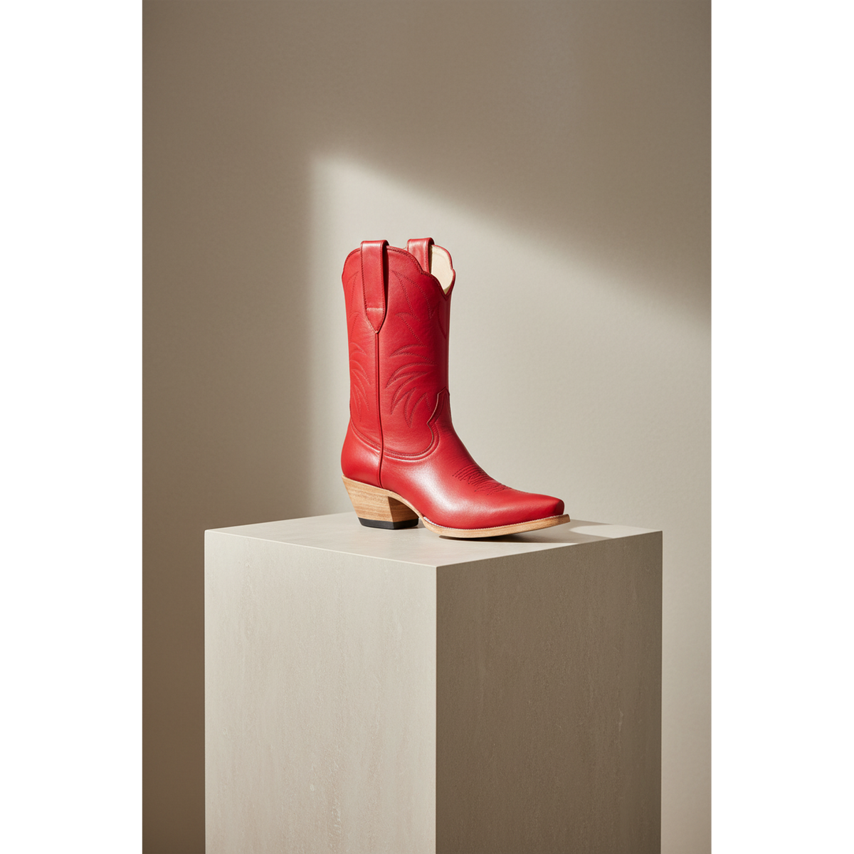 Red midi boot on a tall square pedestal in a sunlit room
