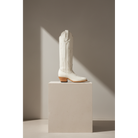 Bone Tulip boot with tonal tulip detailing, side view on a stone pedestal